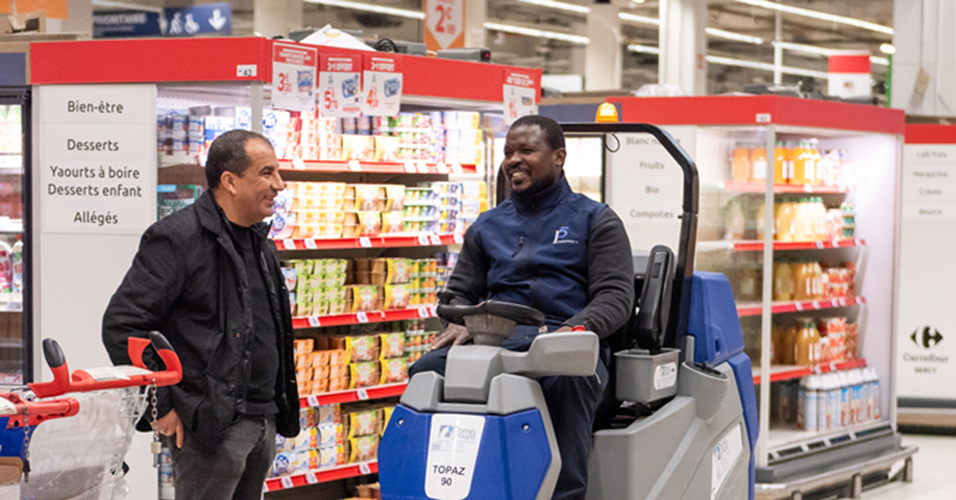 ecoute Un inspecteur et un salarié assis sur une autolaveuse discutent dans une allée de supermarché